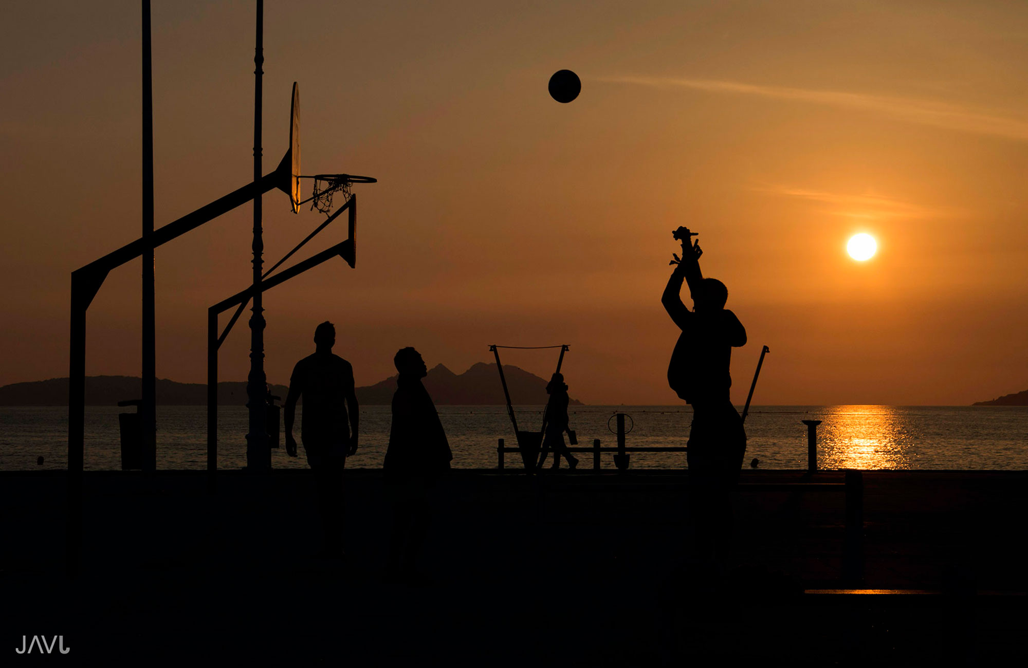 Jugando al baloncesto en la playa de samil durante la puesta de sol